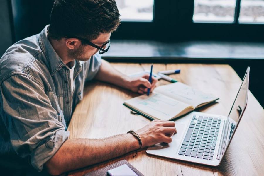Writer preparing an article beside a laptop